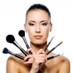 Beautiful woman with makeup brushes